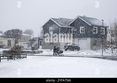 Famiglia non riconosciuta con bambini che camminano all'esterno durante la tempesta di neve pesante nel villaggio di Vik in Islanda Foto Stock