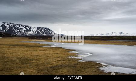 Tipico islandese drammatico paesaggio con lago ghiacciato e montagne coperte di neve in Islanda Foto Stock