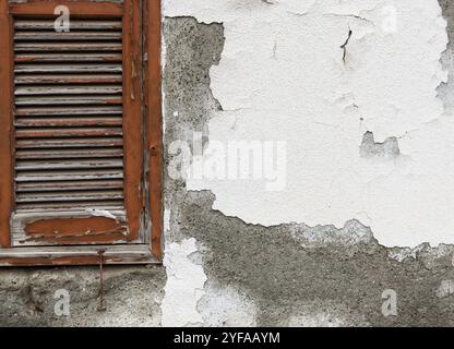 Vecchia finestra di legno colorato chiusa di rosso su una parete di cemento grunge bianco Foto Stock