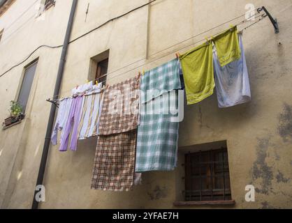 Servizio di lavanderia a domicilio con abiti colorati appesi su una corda all'esterno di una casa per asciugarsi Foto Stock