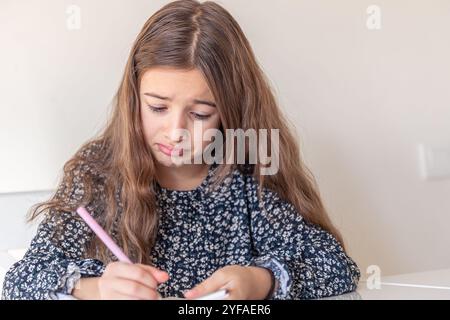 Una ragazza triste disegna un taccuino. I compiti a casa. Foto Stock