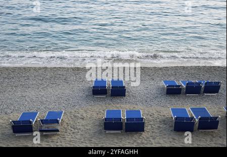 Gruppo di sdraio rilassanti sulla spiaggia blu su una costa sabbiosa vuota Foto Stock