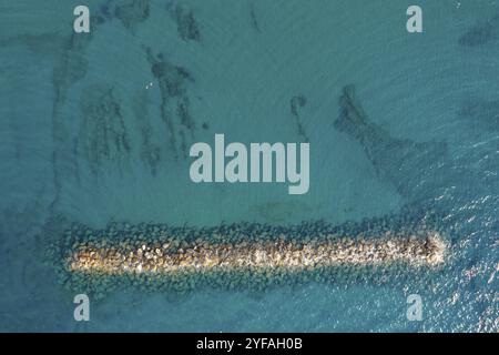 Vista aerea da un drone volante di acqua blu e frangiflutti. Muro marino Paphos Cipro Foto Stock