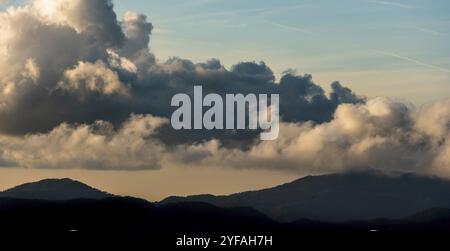 Silhouette di cime montane con nebbia e nuvole drammatiche. Tramonto colorato. Troodos montagne cipro Foto Stock