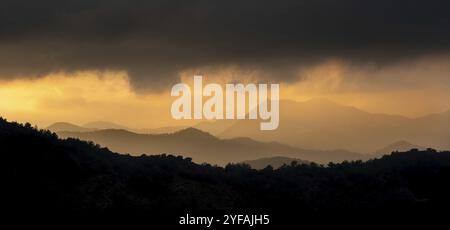 Tramonto con cielo nuvoloso e drammatica luce del sole arancione sopra montagna Troodos montagne Cipro Foto Stock