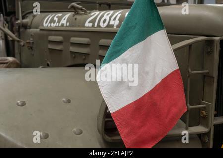 Bandiera italiana che sventola su una jeep vintage dell'esercito americano, simboleggia il coraggio durante la guerra, catturando lo spirito della ricca storia militare italiana Foto Stock