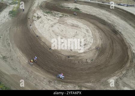 Drone aereo di una gara di motocross su una pista sportiva sterrata e sinuosa. Vista aerea delle corse ad alta velocità. Atleti in azione Foto Stock