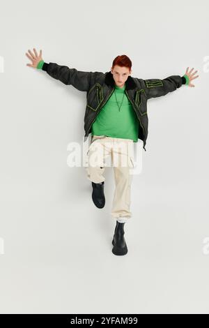 Un giovane uomo dai capelli rossi brillanti indossa elegantemente un cappotto invernale in un luminoso ambiente da studio. Foto Stock