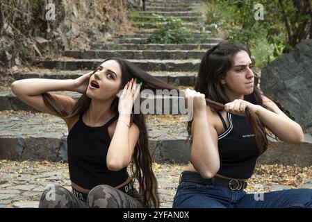 Due donne che lottano e si tirano i capelli mentre sono sedute su una scala Foto Stock