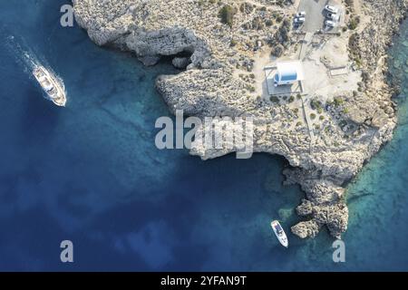 Foto aerea del drone della penisola di Capo Greko con la chiesa di Agioi Anargyroi sulle rocce. Crociera barche turistiche vela. Acque turchesi dell'oceano Foto Stock