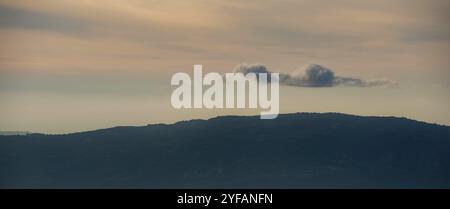 Silhouette di cime montane con nebbia e nuvole drammatiche. Tramonto colorato. Troodos montagne cipro Foto Stock