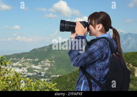 Donna con zaino che scatta foto in montagna Foto Stock