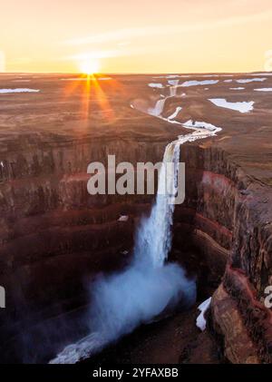 Splendida vista al tramonto di una maestosa cascata che si getta in un profondo canyon, creando una scena mozzafiato di bellezza naturale in Islanda. Foto Stock