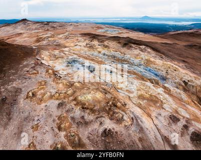 Vista aerea dell'area geotermica di Hverir, Islanda, con piscine geotermali blu e arancione e pozzi di fango in un paesaggio surreale. Foto Stock