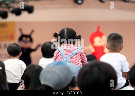 Mizumaki, Fukuoka, Giappone - 26 ottobre 2024: Bambini seduti sulle spalle dei genitori per assistere allo spettacolo di Anpanman al Mizumaki Cosmos Festival Foto Stock