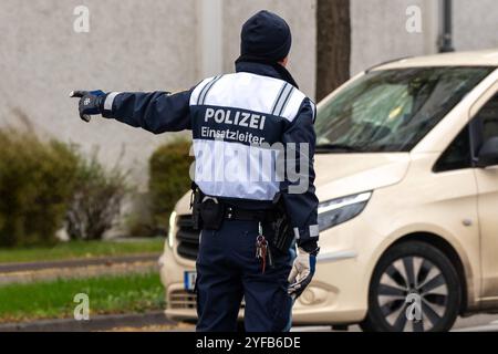 Augusta, Baviera, Germania - 4 novembre 2024: Ufficiale di polizia o ufficiale di polizia del controllo operativo, o capo delle operazioni della polizia bavarese in Svevia di Augusta, incarica CAB di fermarsi, allo sciopero di allerta DELL'UOMO DELL'IG Metall. *** Polizist bzw. Polizeibeamter der Einsatzleitung, bzw. Einsatzleiter der bayrischen Polizei ad Augusta Schwaben, weist taxi zum Anhalten ein, beim IG Metall Warnstreik der MAN. Foto Stock