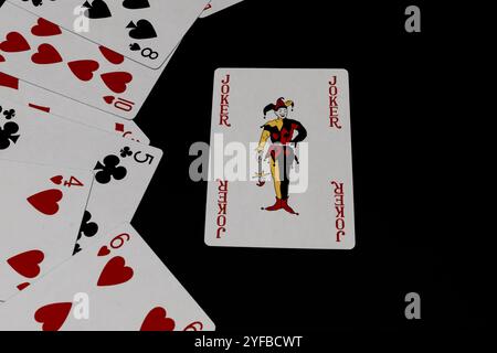 Carte da gioco e carta da jolly isolate su sfondo nero, giornata nazionale di gioco delle carte Foto Stock