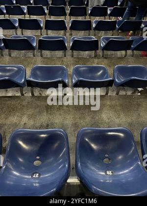 posti a sedere vuoti blu per lo stadio con adesivi numerati, per catturare un momento di tranquillità in un'arena altrimenti affollata Foto Stock