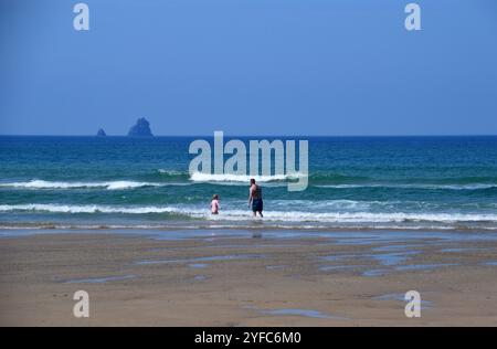 Dad & Daughter in the Sea by Man and His Man Islands (Bawden Rocks) da Perranporth Beach sul Southwest Coastal Path, North Cornwall, Inghilterra, Regno Unito Foto Stock