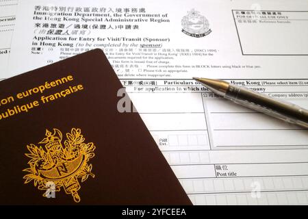 Una penna a sfera e un passaporto francese in cima a un modulo di richiesta di visto per Hong Kong. Foto Stock