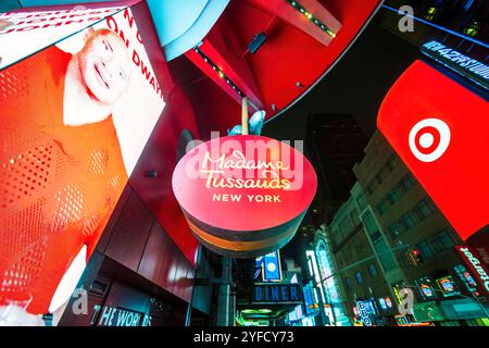 Una vibrante vista notturna della segnaletica illuminata del Madame Tussauds di New York a Times Square, circondata da luminosi cartelloni digitali e luci al neon. Foto Stock