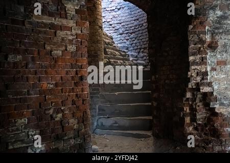 Una stretta scala a chiocciola in mattoni nella fortezza di Bobruisk. La luce del sole all'interno Foto Stock