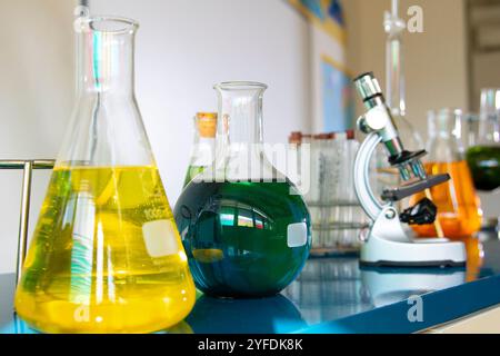 Vista ravvicinata di una configurazione del laboratorio che presenta soluzioni chimiche in varie vetreria, tra cui matracci di Erlenmeyer e matracci A fondo sferico A micros Foto Stock