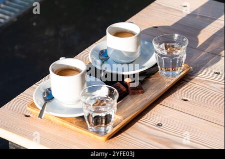 Piatto con due caffè, cioccolato belga e acqua a Koekelberg, Bruxelles, Belgio Foto Stock