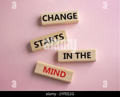 Il cambiamento inizia dal simbolo della mente. Le parole concettuali cambiano iniziano nella mente sui blocchi di legno. Bellissimo sfondo rosa. Il business e il cambiamento iniziano in t Foto Stock