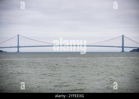 Un'ampia vista del Verrazzano-Narrows Bridge che si estende sull'acqua in una giornata nuvolosa, collegando Staten Island e Brooklyn a New York City. Foto Stock