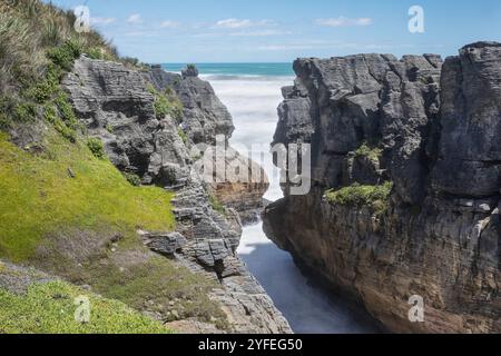 Due ripide scogliere con uno spazio intermedio con acqua di mare che precipita. Foto Stock