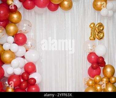 Palloncini colorati luminosi su sfondo bianco per un compleanno di diciotto anni. Uno striscione natalizio con il numero 18. Foto Stock