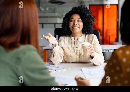 Una donna d'affari fiduciosa guida team diversificati in un ufficio moderno, impegnata in discussioni vivaci e nella definizione di strategie per un progetto di successo. Lavoro di squadra e creazione Foto Stock