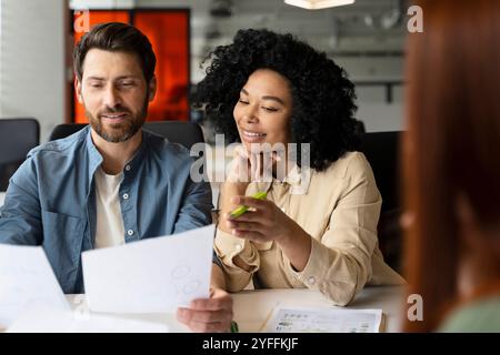 Uomo d'affari e donna d'affari sorridono mentre lavorano insieme in ufficio e rivedono i documenti Foto Stock