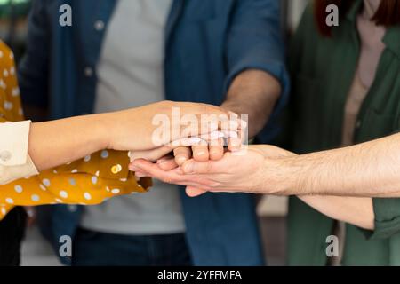 Diversi gruppi di professionisti si uniscono per mano in un gesto di unità e di lavoro di squadra Foto Stock