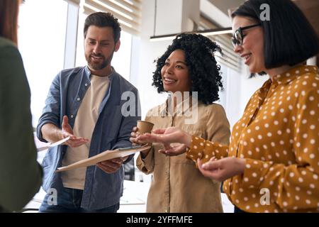 Un gruppo di uomini d'affari si trova in un ufficio, impegnato in una discussione vivace e informale Foto Stock