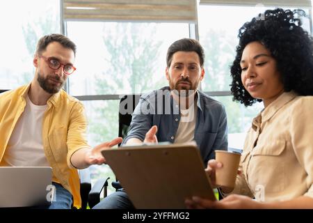 Il team di uomini d'affari sta organizzando riunioni produttive, discutendo strategie e analizzando i dati su una clipboard Foto Stock