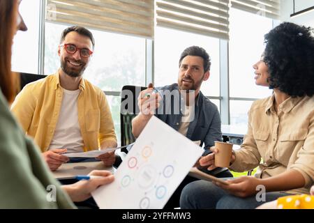 Il team di professionisti aziendali sta organizzando una riunione produttiva, si sta impegnando in una discussione su un nuovo progetto e analizzando grafici e grafici Foto Stock