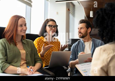 Un gruppo di giovani professionisti sta avendo un incontro produttivo in un ufficio moderno, brainstorming idee e collaborando a un progetto Foto Stock