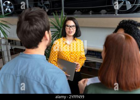 Il responsabile della concessionaria di auto ha in mano un notebook e presenta una nuova vettura a un gruppo di potenziali clienti Foto Stock