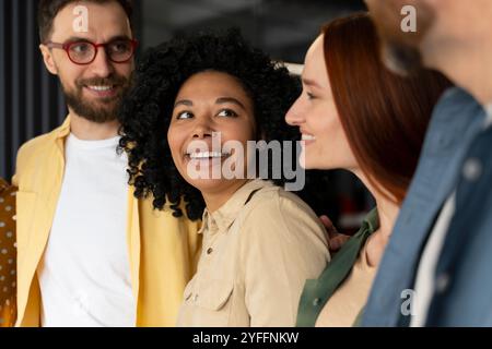 Un gruppo di persone d'affari diverse si sta avvicinando e sorride mentre ascolta i colleghi Foto Stock