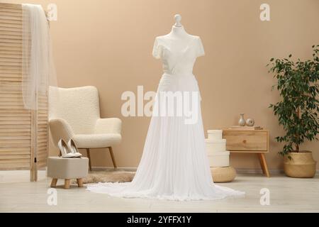 Bellissimo abito da sposa con manichino e scarpe in boutique Foto Stock