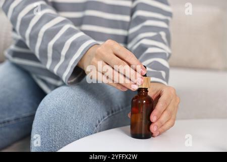 Giovane donna che prende tintura CBD a tavola bianca, primo piano Foto Stock