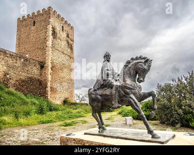 Una statua equestre di Ibn Qasi, proclamato leader politico e spirituale del regno taifa di Mertola, con la torre del castello di Mertola Foto Stock