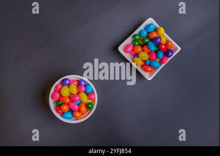 Palle di gomma da masticare di diversi colori in contenitori lucidi in terracotta con uno sfondo colorato omogeneo per il posizionamento del testo Foto Stock