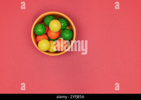 Palle di gomma da masticare di diversi colori in contenitori lucidi in terracotta con uno sfondo colorato omogeneo per il posizionamento del testo Foto Stock