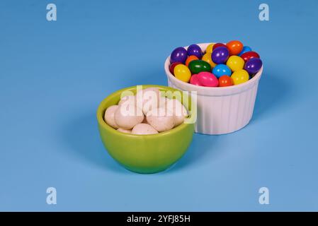 Palle di gomma da masticare di diversi colori in contenitori lucidi in terracotta con uno sfondo colorato omogeneo per il posizionamento del testo Foto Stock