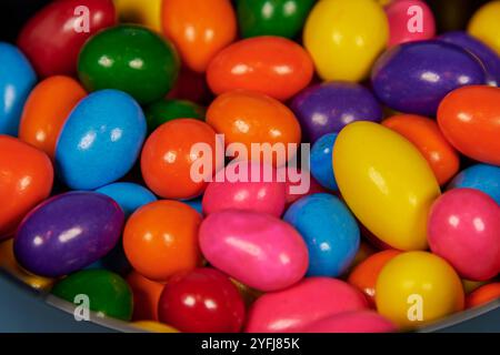 Palle di gomma da masticare di diversi colori in contenitori lucidi in terracotta con uno sfondo colorato omogeneo per il posizionamento del testo Foto Stock