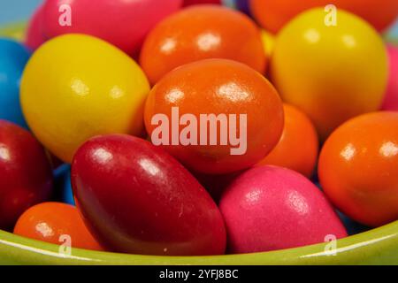 Palle di gomma da masticare di diversi colori in contenitori lucidi in terracotta con uno sfondo colorato omogeneo per il posizionamento del testo Foto Stock