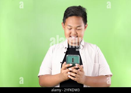 Asian Boy sovrappeso che tiene Samrtphone, isolato su sfondo verde Foto Stock